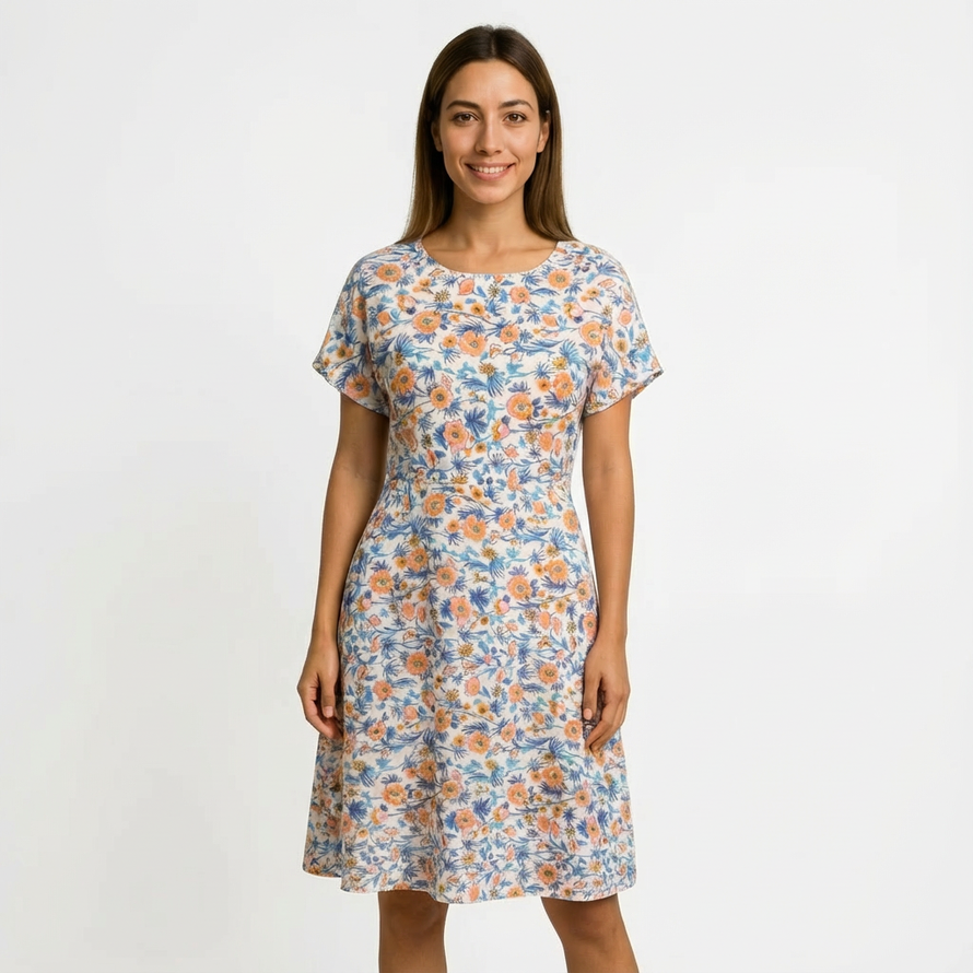 Woman in a white cotton floral dress with orange and blue flowers, short sleeves, and a round neck.