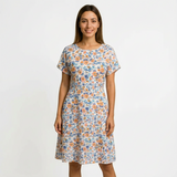 Woman in a white cotton floral dress with orange and blue flowers, short sleeves, and a round neck.