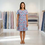 Woman in a light blue cotton dress with pink floral print, short sleeves, and a round neck.