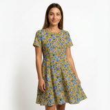 Woman in a short-sleeve mustard yellow dress with a blue floral print.