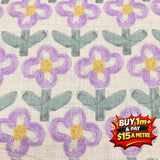 Hanako cotton printed poplin fabric with purple and yellow flowers and green leaves on a white background.