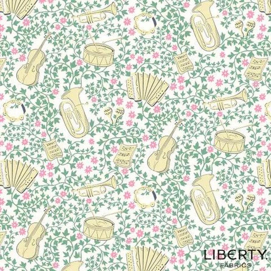 Liberty Garden Party L01667337C fabric: cream musical instruments on a white background with pink flowers and green vines.