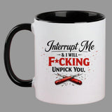 A white ceramic coffee mug with a black handle and black interior, featuring a humorous graphic that reads 'Interrupt Me & I WILL F*CKING UNPICK YOU.' in black and red lettering with crossed red tools below, set against a solid dark red background.