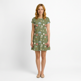 Woman in a short-sleeve STORYBOOK GREEN ALLOVER DV6028 dress with a whimsical purse and mirror pattern.