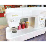 White Sashiko sewing machine with four spools of Silco lint-free cotton thread in orange, rust, yellow, and pink.