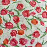 White cotton fabric with a vibrant print of red and orange tulips and green leaves.
