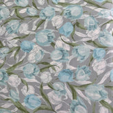 Grey cotton fabric with a print of blue and white tulips and green leaves.