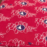 Red ironing board cover with floral pattern on a wooden surface, featuring Guttermann branding.