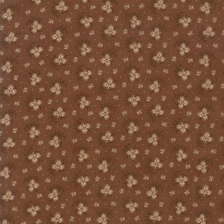 A close-up of a brown fabric or wallpaper pattern featuring a repeating design of small beige flowers, dark brown thistle-like accents, and tiny white dots.
