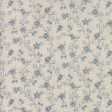 A close-up of a fabric or wallpaper pattern featuring a delicate blue floral vine design on a warm cream background.