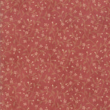 A close-up of a dusty rose red fabric or wallpaper featuring a delicate repeating pattern of light tan vines, leaves, and small white flowers.