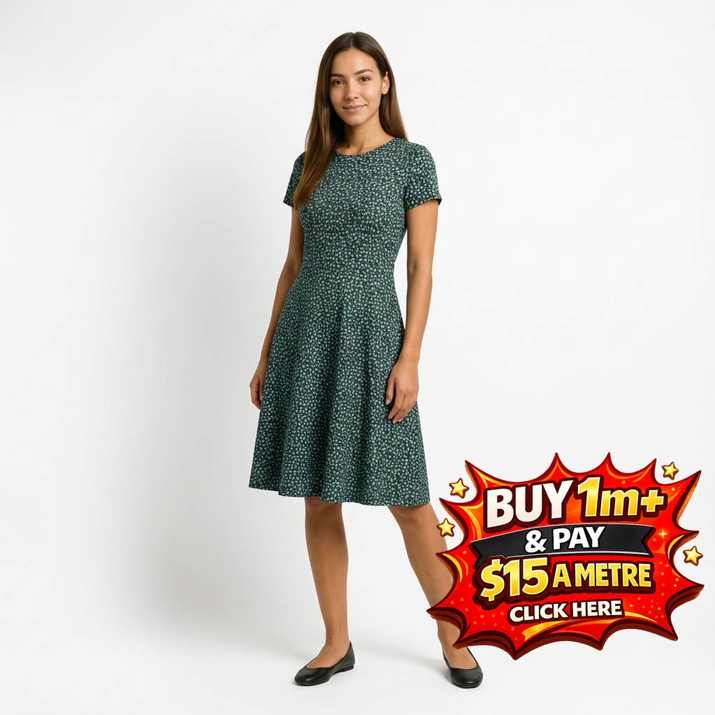 Woman in a dark green floral print short-sleeve dress with a flared skirt, wearing black flats.