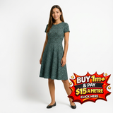 Woman in a dark green floral print short-sleeve dress with a flared skirt, wearing black flats.