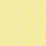 A close-up of a yellow fabric or material with a dense white floral and dot pattern covering the full frame.