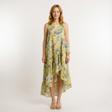 Woman in a yellow cotton lawn dress with a floral print, high-low hem, and ruffled details.