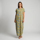 Woman in a yellow cotton maxi dress with blue floral print, short sleeves, and round neck.