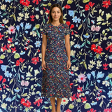 Woman in a navy blue cotton lawn dress with a vibrant red, blue, and white floral print.