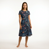 Woman wearing a navy cotton lawn dress with a vibrant floral print, short sleeves, and a boat neck.