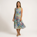 Woman in a sleeveless, knee-length cotton dress with a vibrant floral print on a light background.