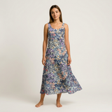 Woman wearing a sleeveless, flowy cotton lawn dress with a blue, purple, and pink floral print.