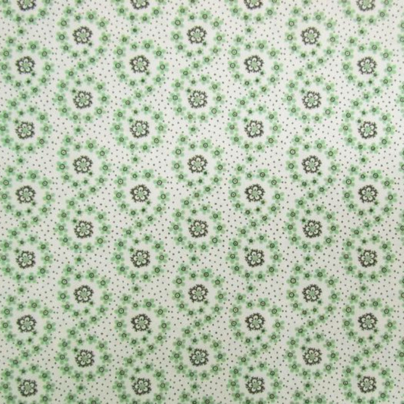 A close-up of a fabric pattern featuring a repeating design of green and brown floral medallions on a white background with fine black speckles.