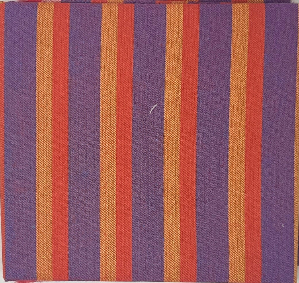 Striped fabric sample on a white sheet with a wooden surface and papers in the background