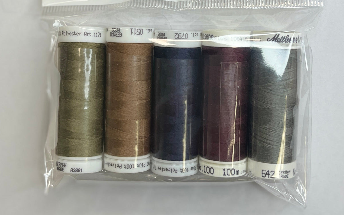 Set of brown thread spools in a clear plastic package on a white surface.