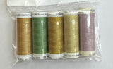 Set of thread spools in a clear package on a white surface with a pen and floral-patterned object.