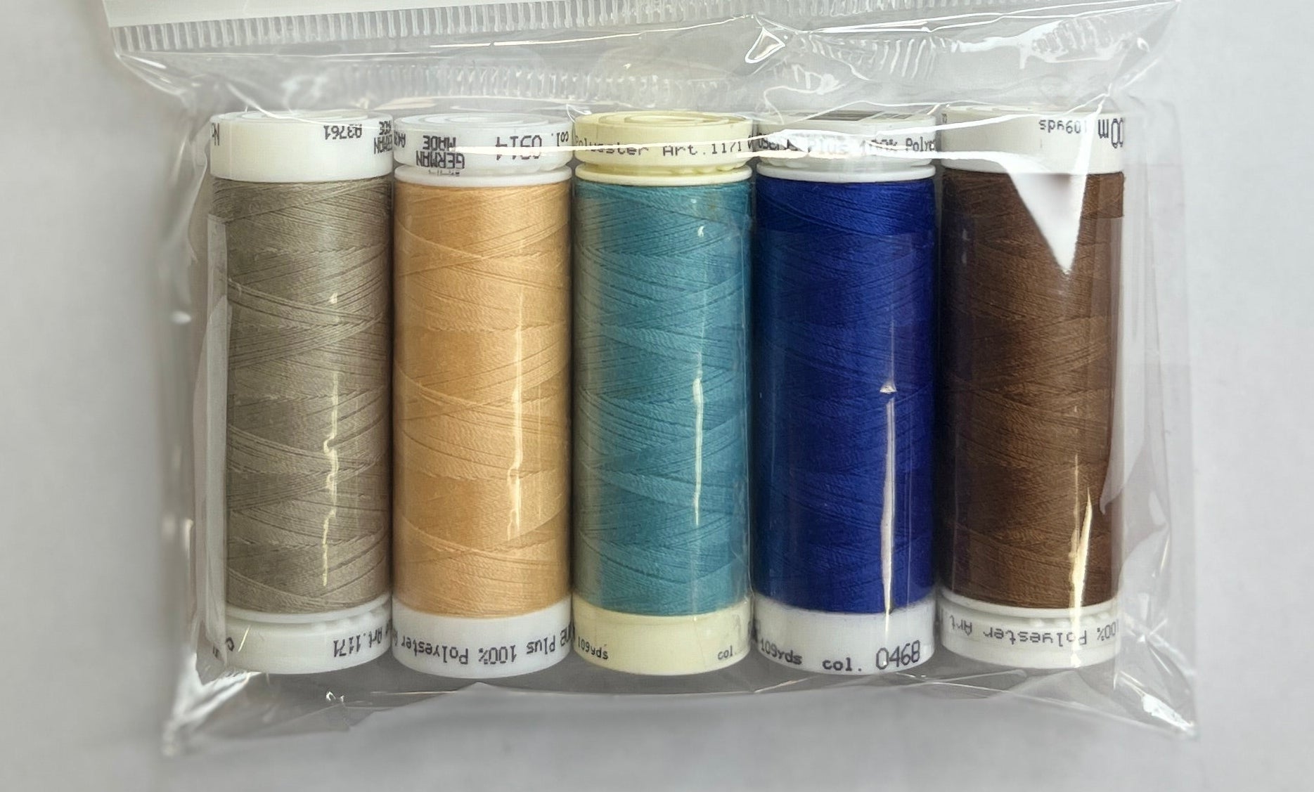 Set of thread spools in a clear package with a label on a white surface.