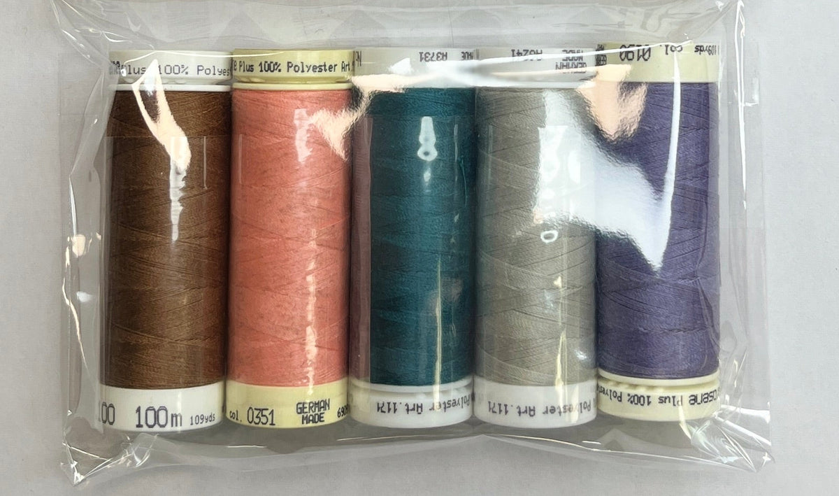 Set of colorful thread spools in a clear package on a white surface with a wooden edge.