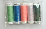 Set of colorful thread spools in a clear package on a white sheet of paper with a wooden surface.
