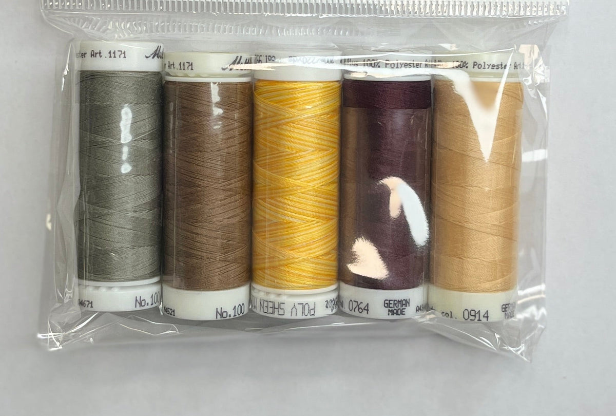 Packaged thread set with spools on a white sheet of paper