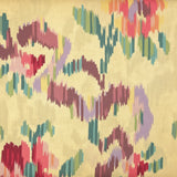 A folded piece of fabric with a multicolor ikat pattern on a cream background, displayed on a wooden surface.