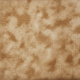 A close-up of a light beige fabric with a soft, mottled pinkish-beige pattern, with other patterned fabrics stacked above it.