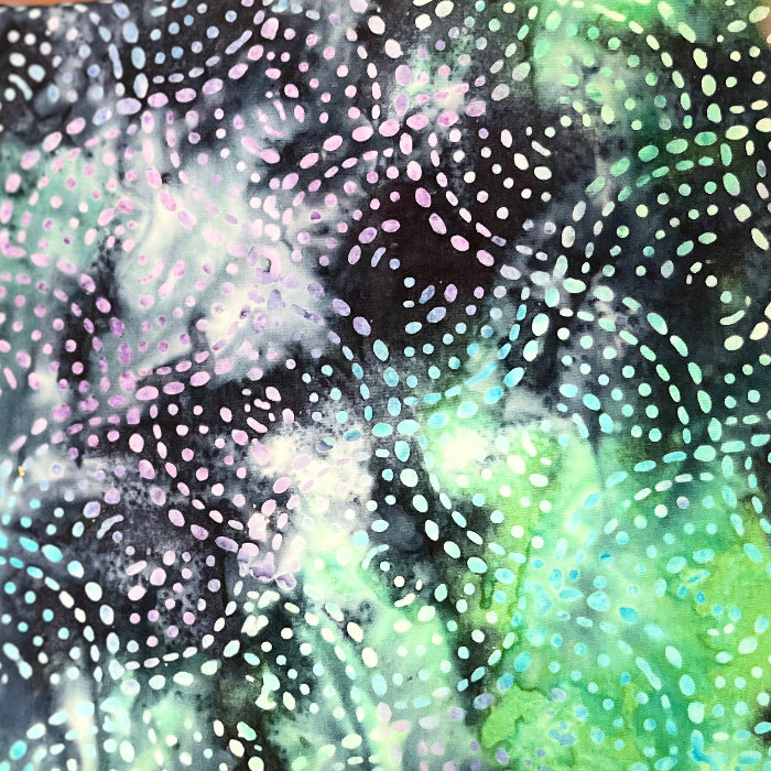 A close-up of a patterned fabric or material being held up by a hand. The surface has an abstract design with swirling marbled areas in black, green, purple, and white, overlaid with dotted circular motifs.