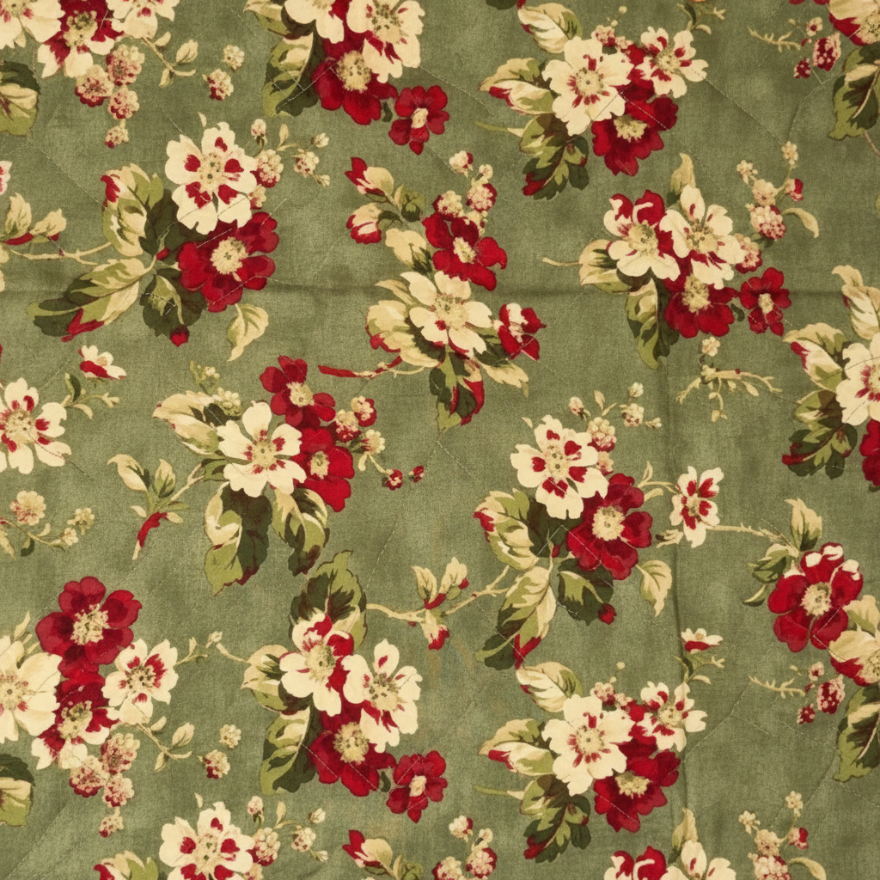 A close-up of a floral fabric pattern featuring red and cream flowers with green leaves on a muted sage green background.