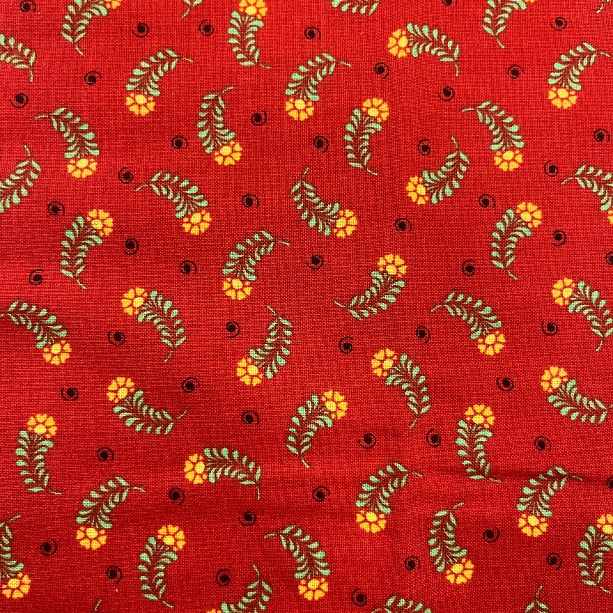Red cotton fabric with a repeating pattern of yellow flowers, olive green leaves, and small black dots.
