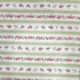 A close-up of a striped fabric or wallpaper pattern featuring horizontal bands of green, white, and red floral motifs, held by a hand.