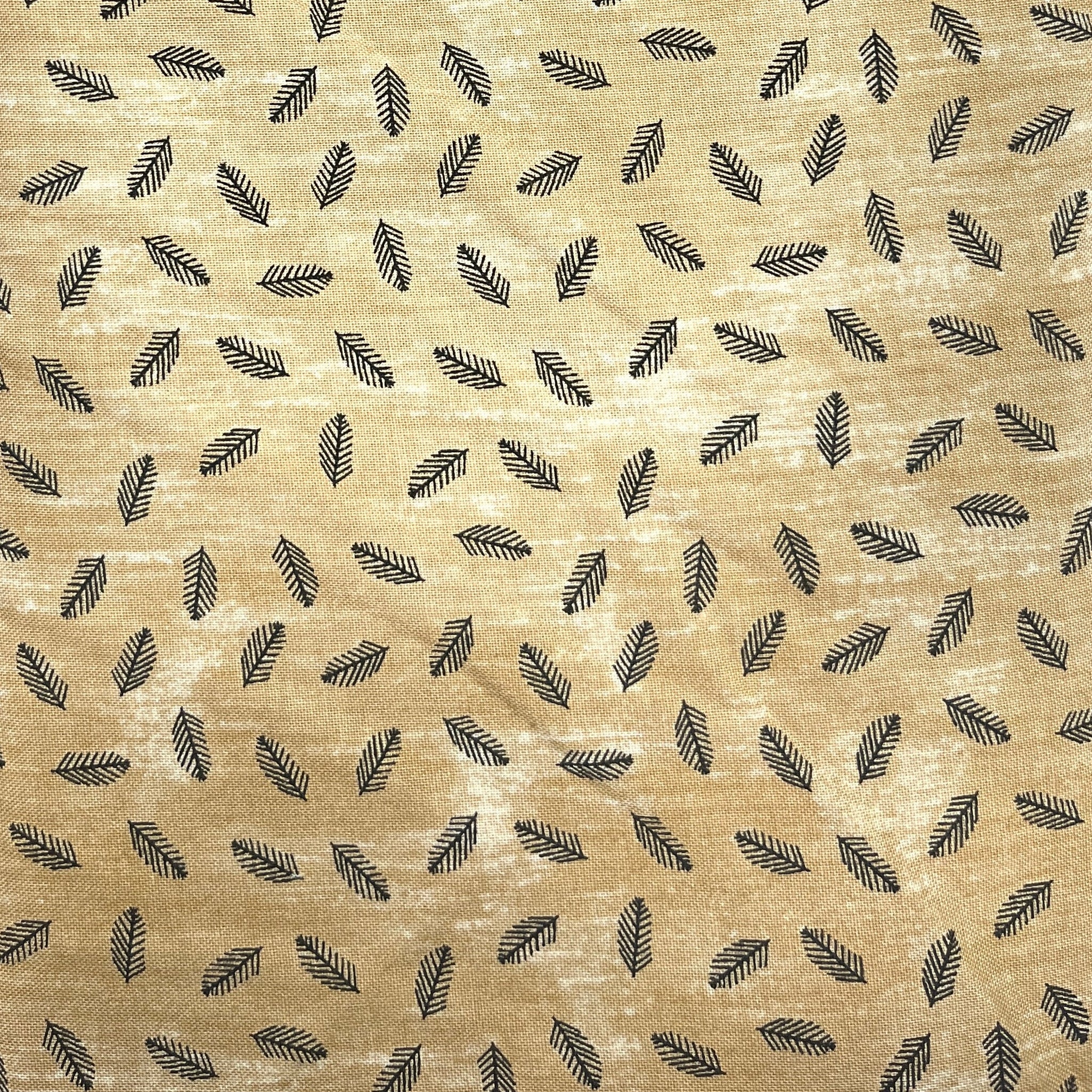 A close-up of a beige fabric with a repeating pattern of small black feather-like shapes, laid flat on a dark wooden surface.