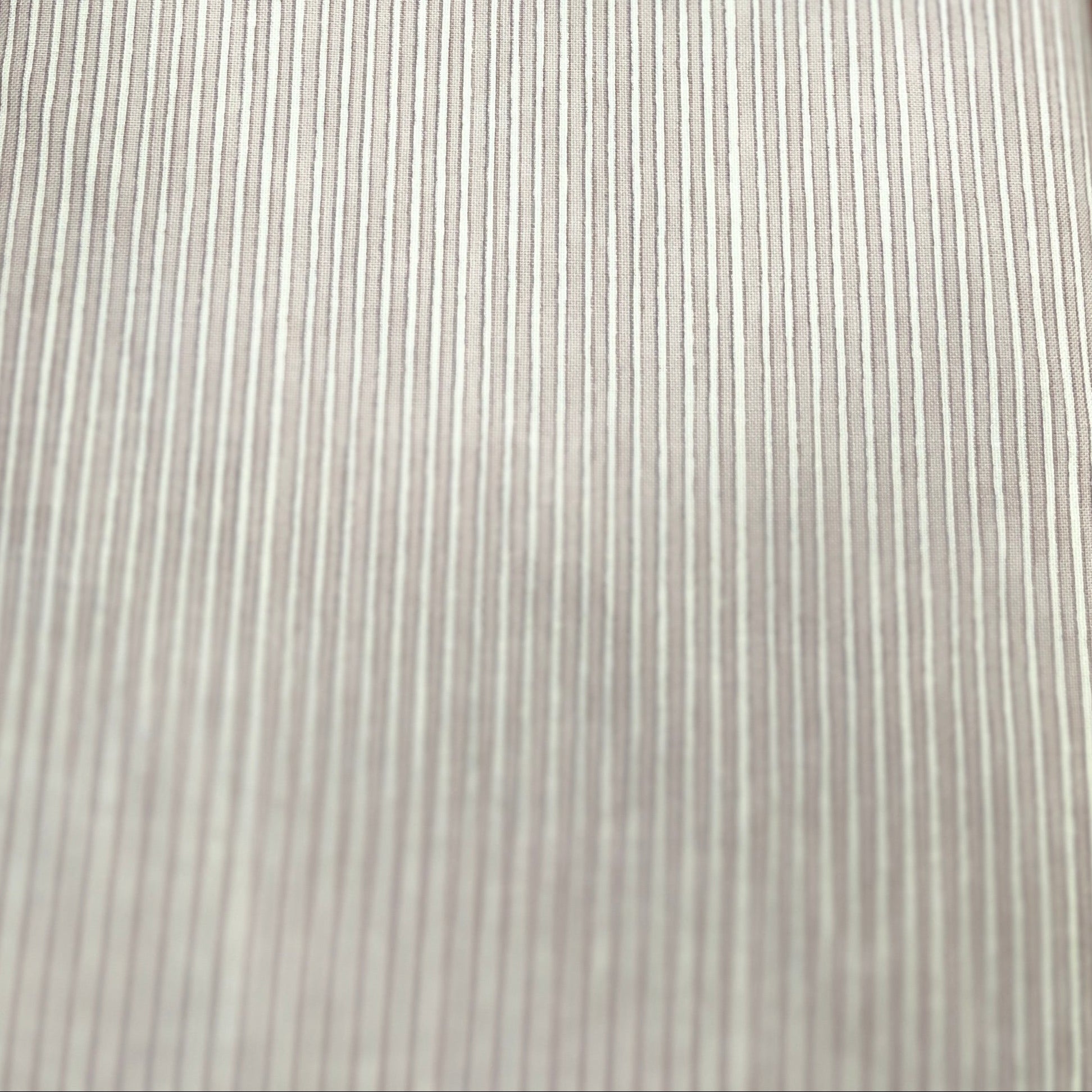 A close-up of a light gray ribbed fabric or material sample laid flat on a wooden surface.