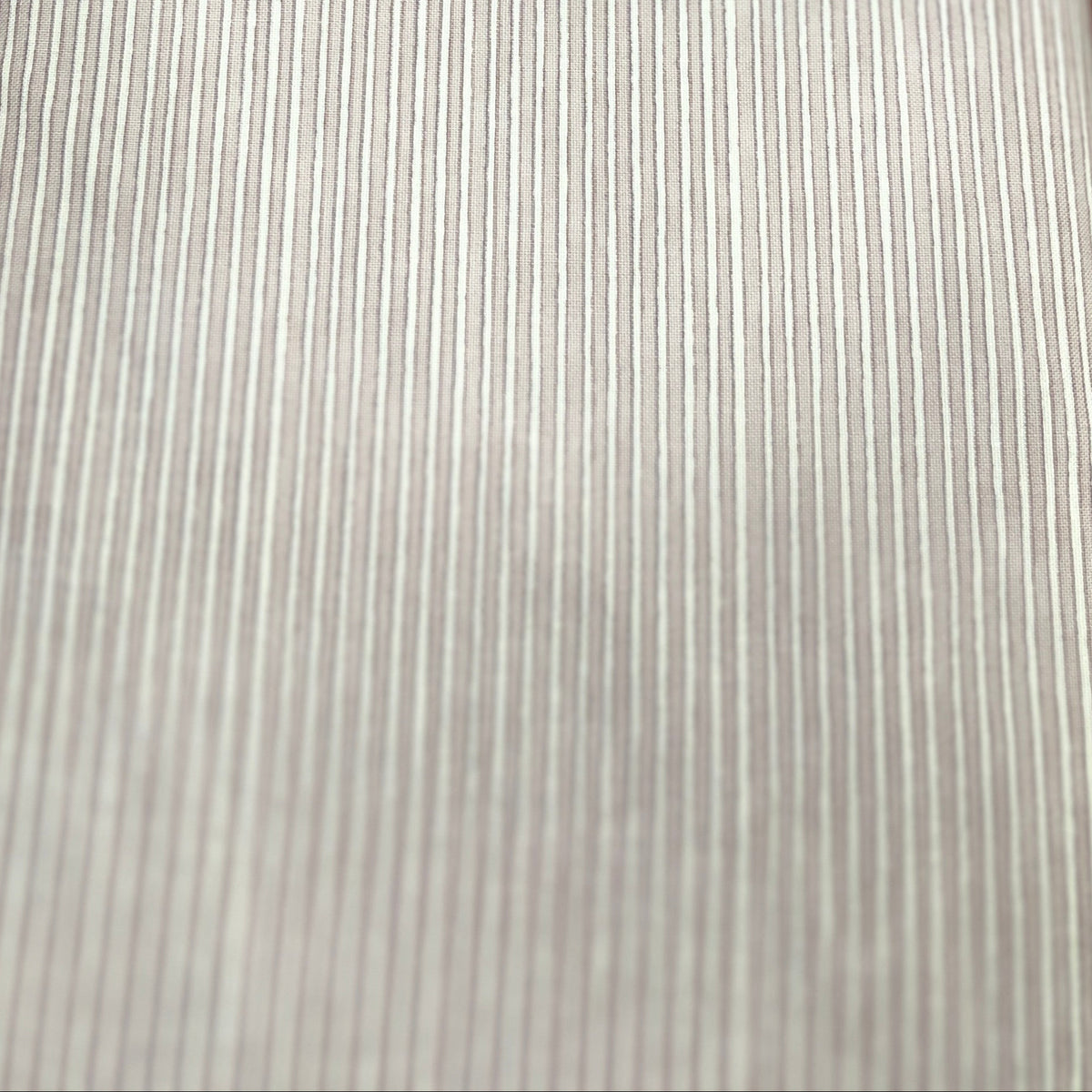 A close-up of a light gray ribbed fabric or material sample laid flat on a wooden surface.