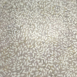 A close-up of a textured surface with a dense speckled pattern of small beige, white, and light brown dashes on a warm taupe-beige background.