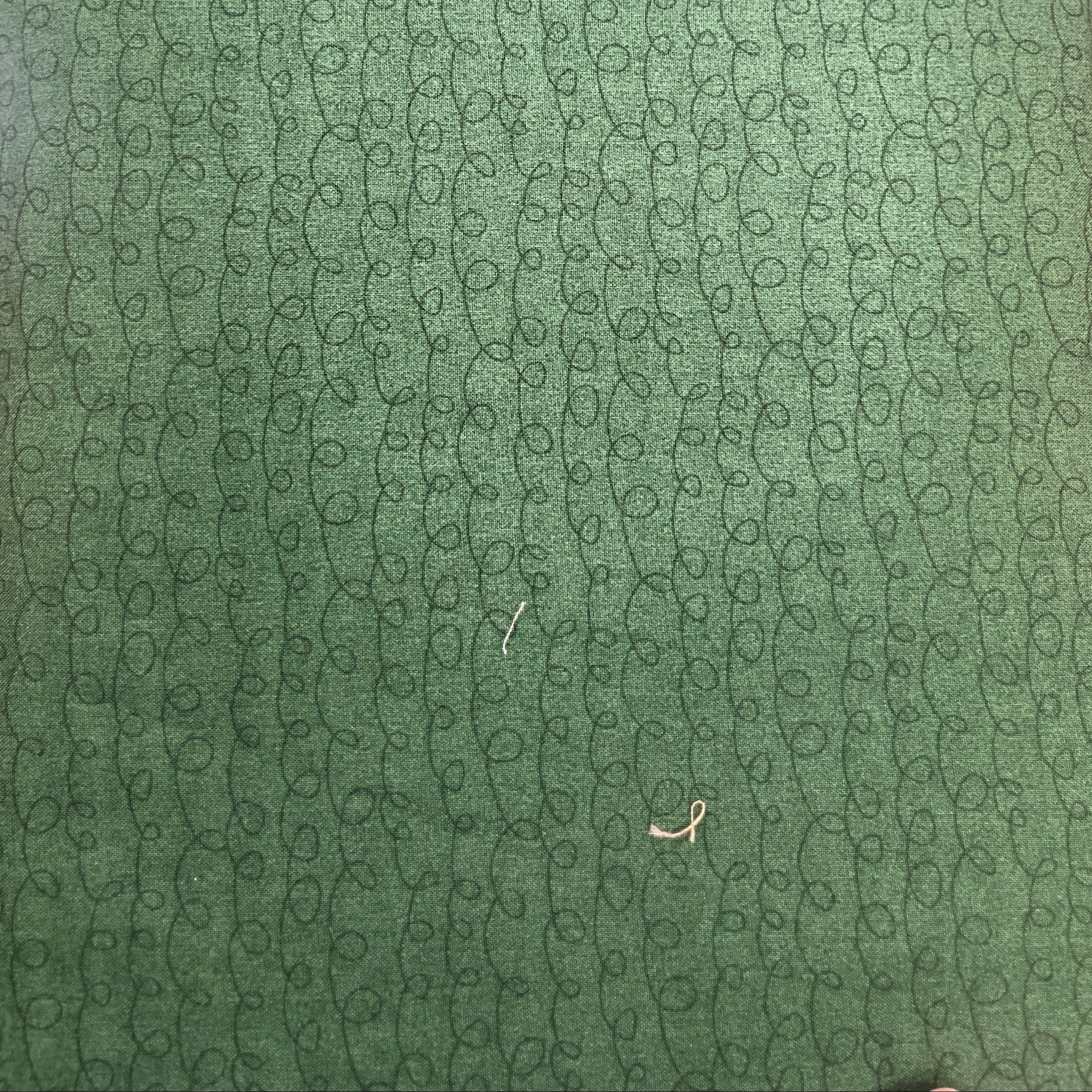 A close-up of a green textured surface with a repeating circular pattern, photographed indoors on a wooden table.