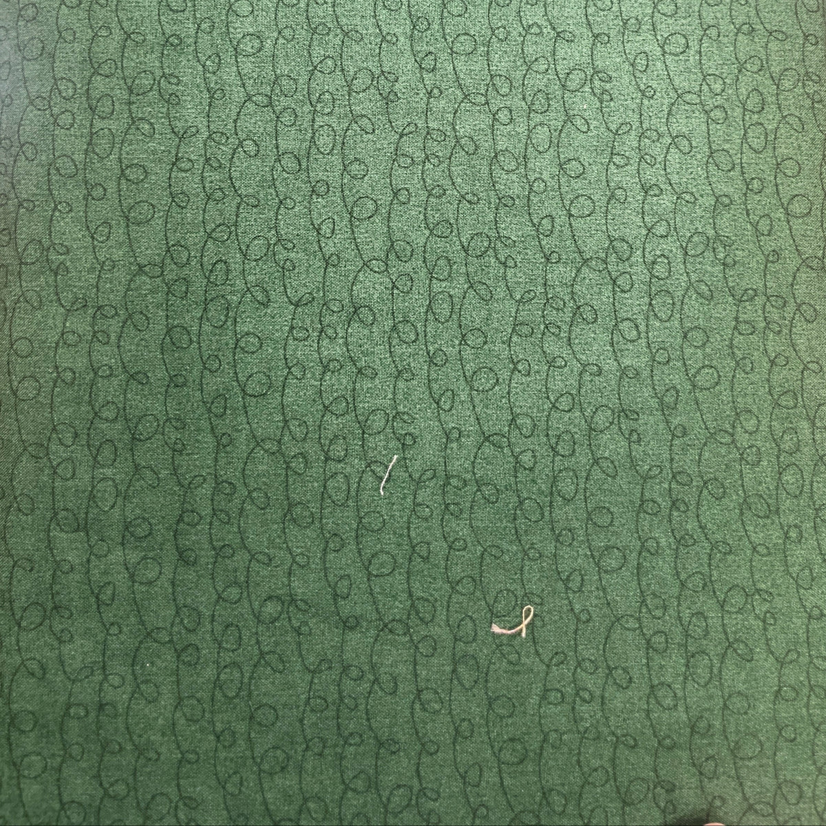 A close-up of a green textured surface with a repeating circular pattern, photographed indoors on a wooden table.