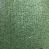 A close-up of a green textured surface with a repeating circular pattern, photographed indoors on a wooden table.