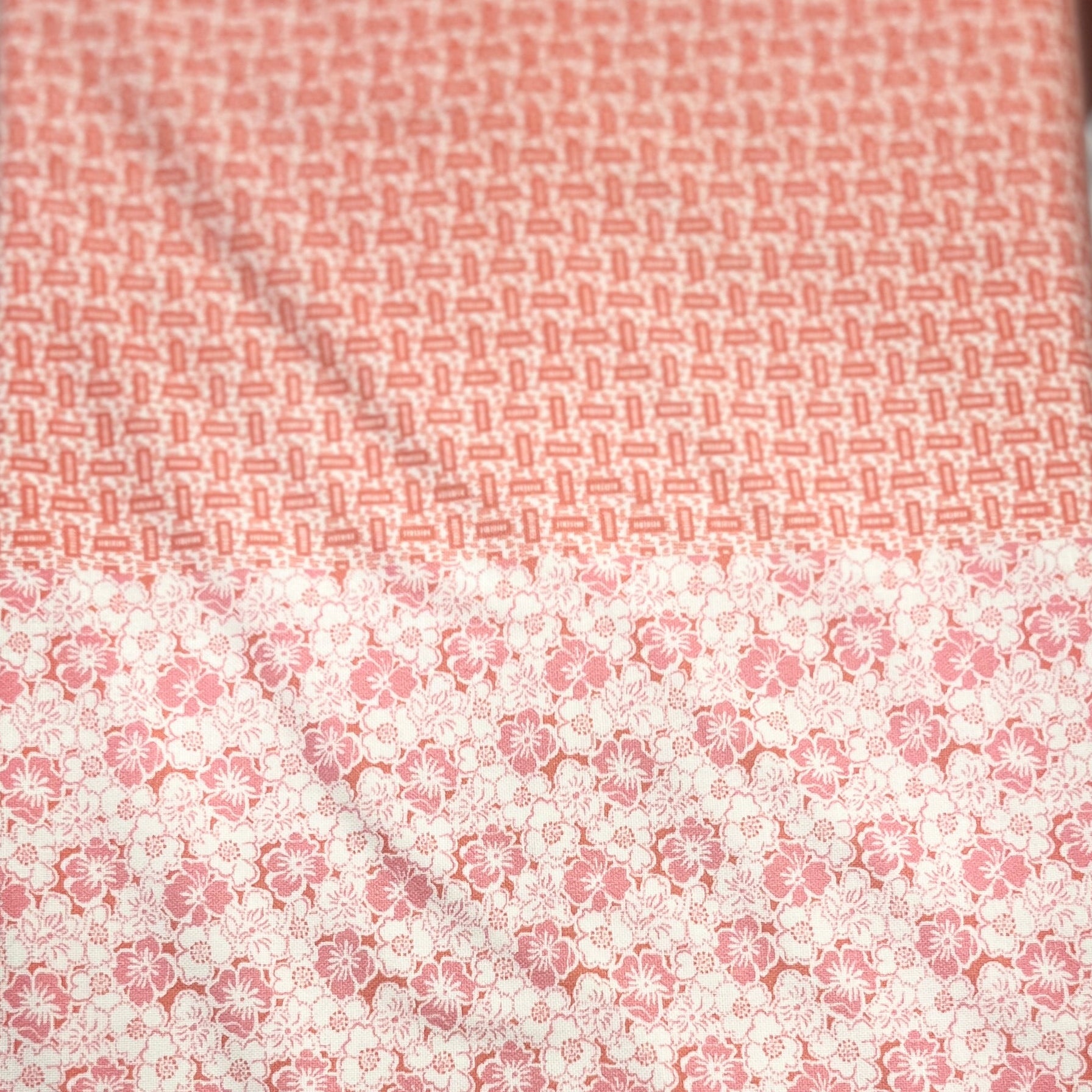 A long rectangular textile item, likely a scarf or bandana, featuring a split design: a fine coral-red geometric pattern on the upper half and a larger pink floral motif on a white background on the lower half.