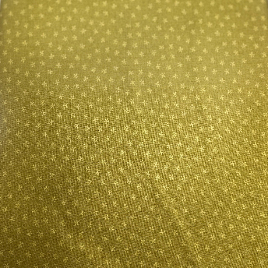 A close-up of a yellow-green fabric item, likely a tie or scarf, featuring a small repeating geometric star pattern in a lighter gold tone.