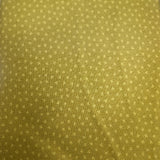 A close-up of a yellow-green fabric item, likely a tie or scarf, featuring a small repeating geometric star pattern in a lighter gold tone.