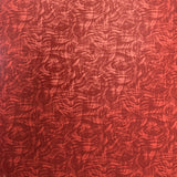 A close-up of a red textured material with an abstract wavy pattern, shown standing vertically with a blurred indoor background.