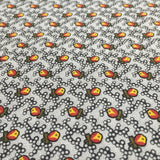 A close-up of a necktie featuring a repeating pattern of small orange and yellow flowers with green leaves on a white background.